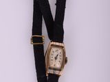 une photo d'une montre-bracelet avec un bracelet noir et une boucle dorée