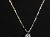 a woman wearing a necklace with a small diamond on it