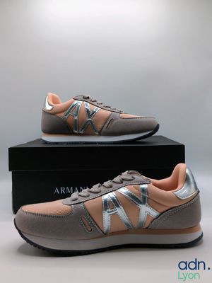une paire de baskets grises et roses posées sur une boîte