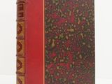 un vieux livre à la couverture rouge posé sur une surface blanche