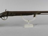 an old gun with a wooden barrel on a clear stand