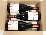 three bottles of wine in a cardboard box on a table