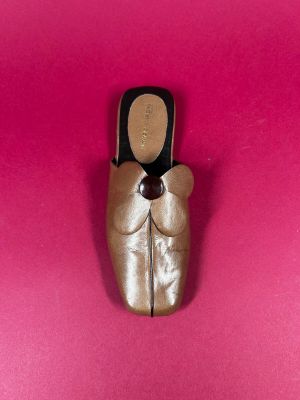 gold ballet shoes on a pink surface with a black bow
