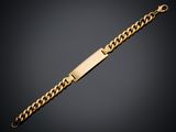 a gold bracelet with a bar and a chain on a black background