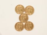 quatre pièces d'or superposées sur une surface blanche