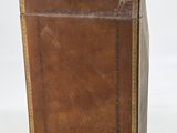 an old suitcase with a leather cover on top of a white surface