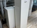 trois grands socles blancs dans un magasin, avec des mannequins en arrière-plan