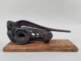 coupe-tube ancien en fonte, posé sur un socle en bois, sur fond blanc