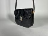 a black crocodile skin purse with a gold clasp