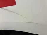 the front bumper of a white car with scratches and scratches on it