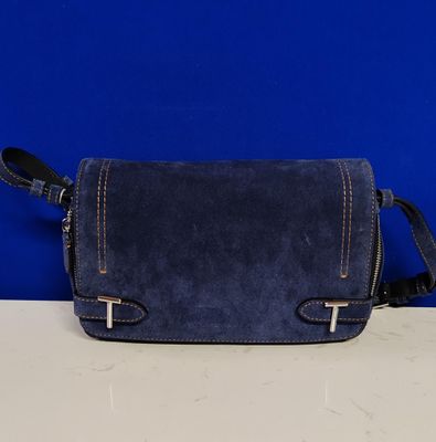 un sac à main bleu posé sur une table près d'un mur bleu