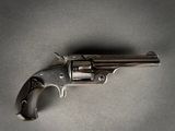 un gros plan d'un revolver posé sur une table, sur fond gris
