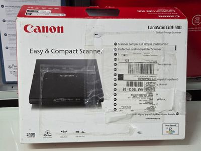 une boîte contenant des scanners Canon, faciles à utiliser et compacts, posée sur une table
