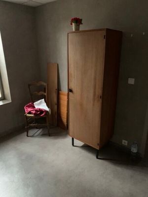 une armoire placée dans un coin de la pièce, avec une chaise à côté