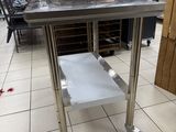 a stainless steel table with a shelf in the middle of a store