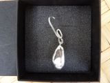 a box with a silver pendant inside of it on a wooden floor