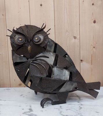 une sculpture en métal représentant un hibou perché sur une table