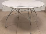 une table en marbre blanc avec des pieds chromés et un plateau blanc