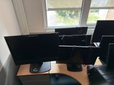 three computer monitors sitting on a desk in front of a window