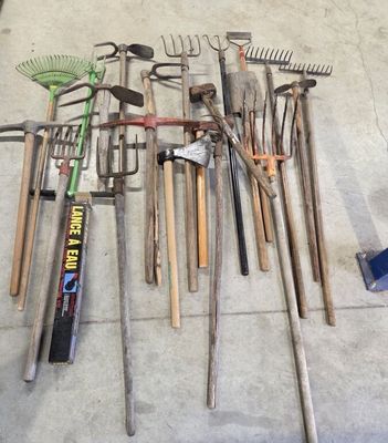 de nombreux outils de jardinage de toutes sortes disposés sur le sol