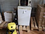un aspirateur jaune posé sur une palette à côté d'une pile de cartons