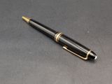 a close up of a pen on a table with a black background