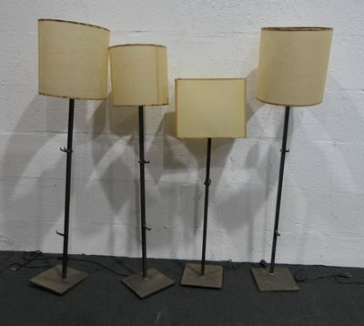 trois lampes posées sur un pied noir, avec un mur blanc en arrière-plan