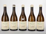 quatre bouteilles de vin sont alignées sur une surface blanche