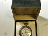 a small silver pocket watch in a box on a table