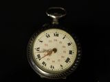 a pocket watch that is sitting on a black surface