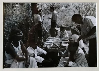 une photo en noir et blanc montrant un groupe de personnes assises autour d'une table