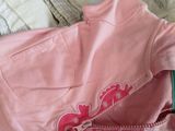 a pink jacket sitting on top of a pile of clothes