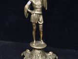 brass figurine of a man holding a torch in his hand
