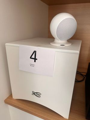 une enceinte blanche posée sur une étagère à côté d'un téléviseur