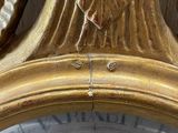 a close up of a gold clock with a leaf on the face