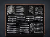 many silver spoons in a wooden box on a table