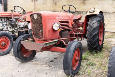 un tracteur rouge garé devant un bâtiment