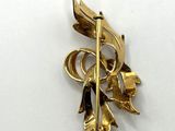 an image of a gold brooch with leaves and flowers on it
