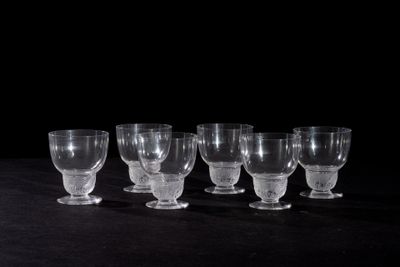 six empty wine glasses lined up on a black table