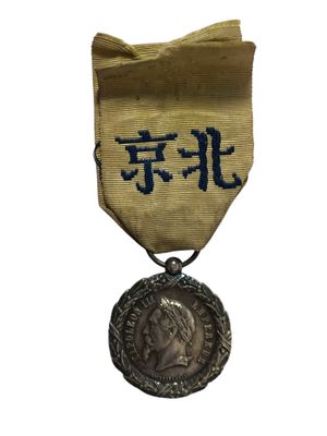 une vieille médaille sur laquelle figure une inscription en chinois et qui est entourée d'un ruban