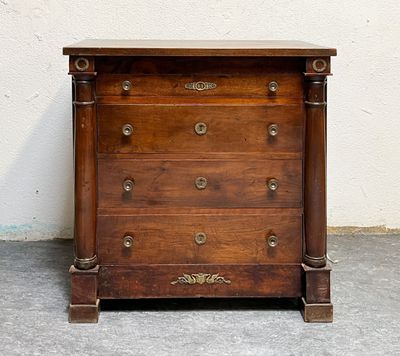 une petite commode en bois posée sur un sol en béton