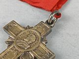 a gold cross on a red ribbon on a table