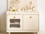 a small wooden toy kitchen with a sink and oven