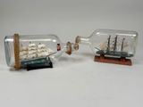 two small model ships in a bottle on a table