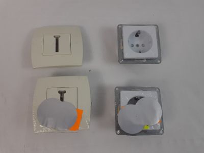 Quatre types différents de prises électriques sont représentés sur une surface blanche