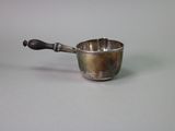 a small silver cup with a handle on a table