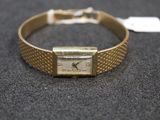 a gold bracelet with a watch on it on a table