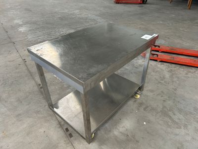 une photo d'une table en acier inoxydable montée sur roulettes dans un entrepôt