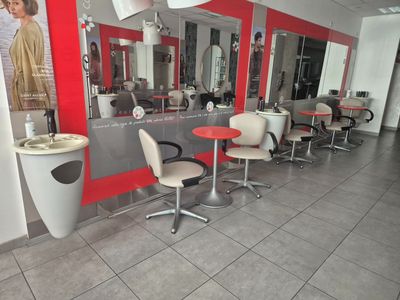une photo d'un salon de coiffure avec des fauteuils et des miroirs