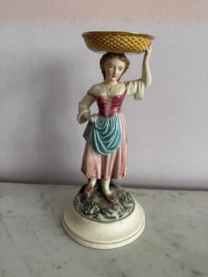 une figurine représentant une femme tenant un panier sur la tête